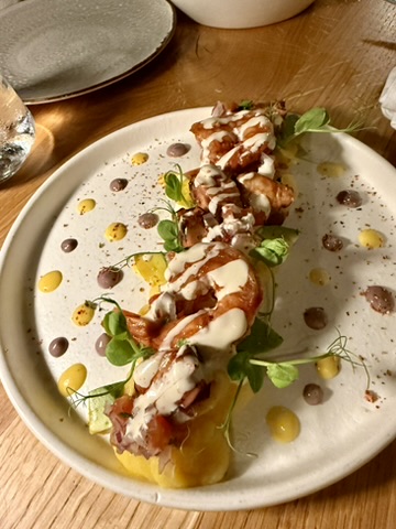 A plated dish with a creamy sauce, microgreens and dots of sauce around it