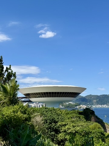 Oscar Niemeyer's white, saucer-shaped museum above green bushes, the bay and hills behind under a blue sky