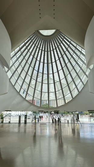 A vast ribbed glass window at the end of a bright white hall, people on the polished floor