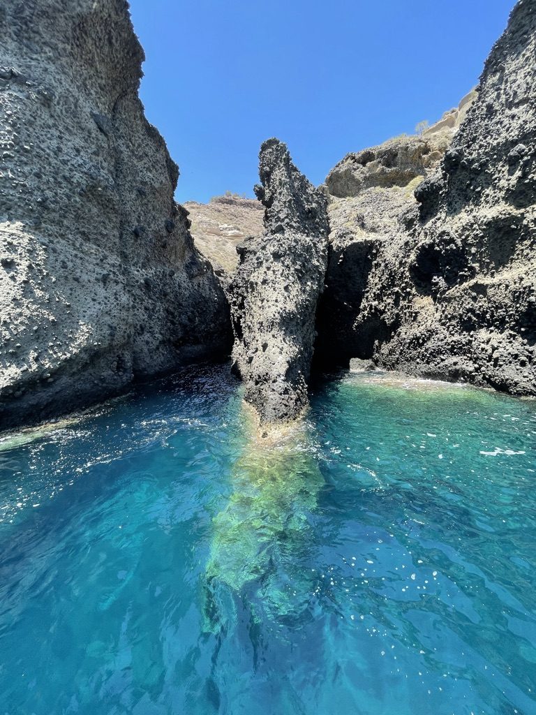 Turquoise water in a sea cave between volcanic rocks, Santorini