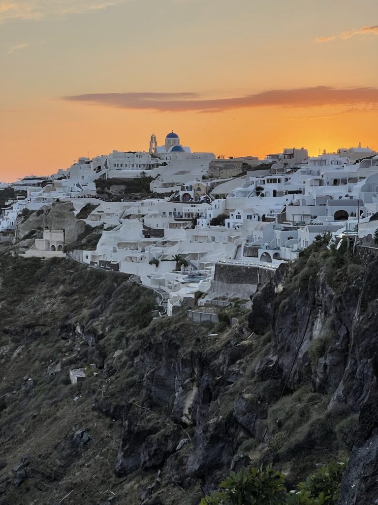 Oia at sunset, a blue dome above white houses on the cliff